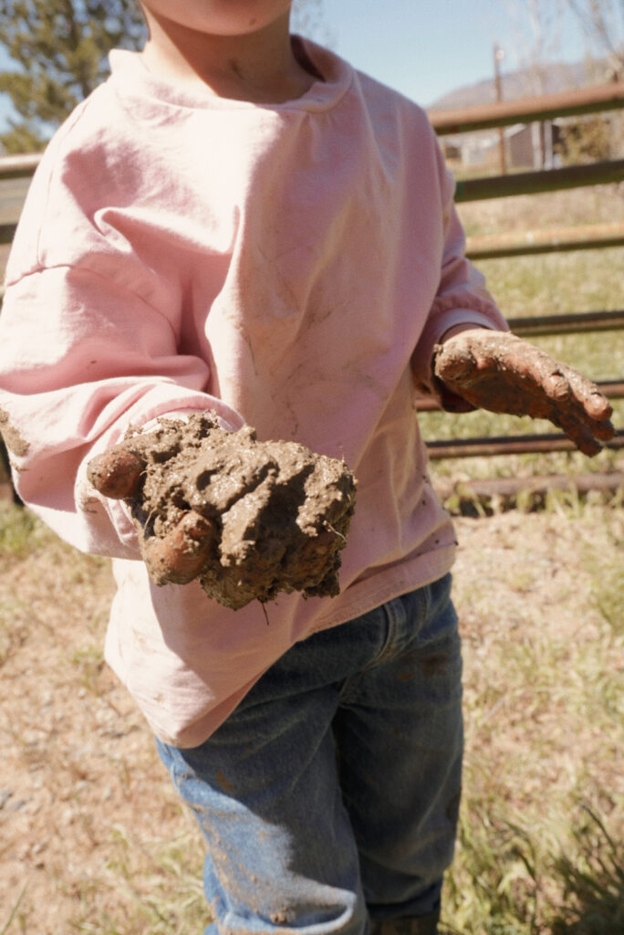 kid in a pink shirt holding mud