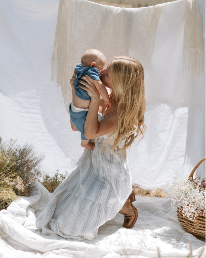 mother and baby sitting on blanket outside summer