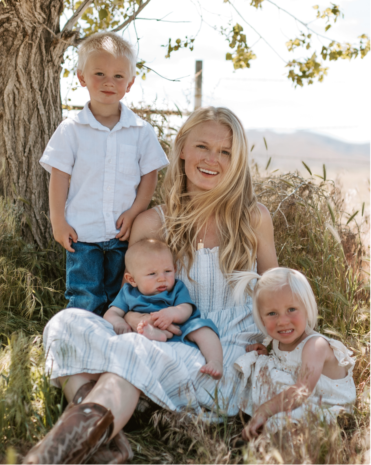 mom and kids sitting outside on a blanket