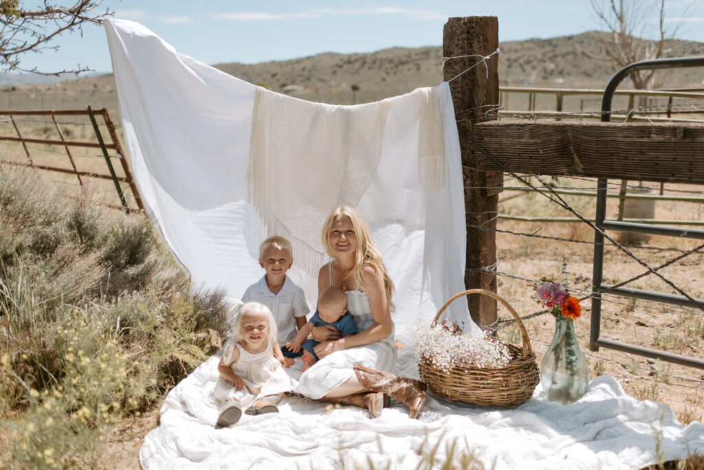 Mom and kid sitting on blanket, basket of flowers